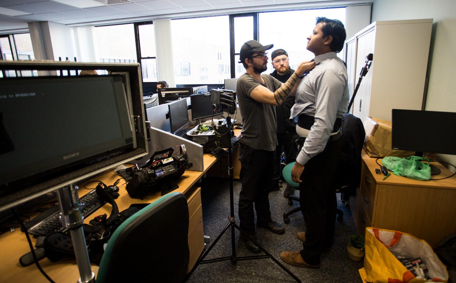 Film crew setting up an office professional for a shoot, showcasing corporate video production behind the scenes.