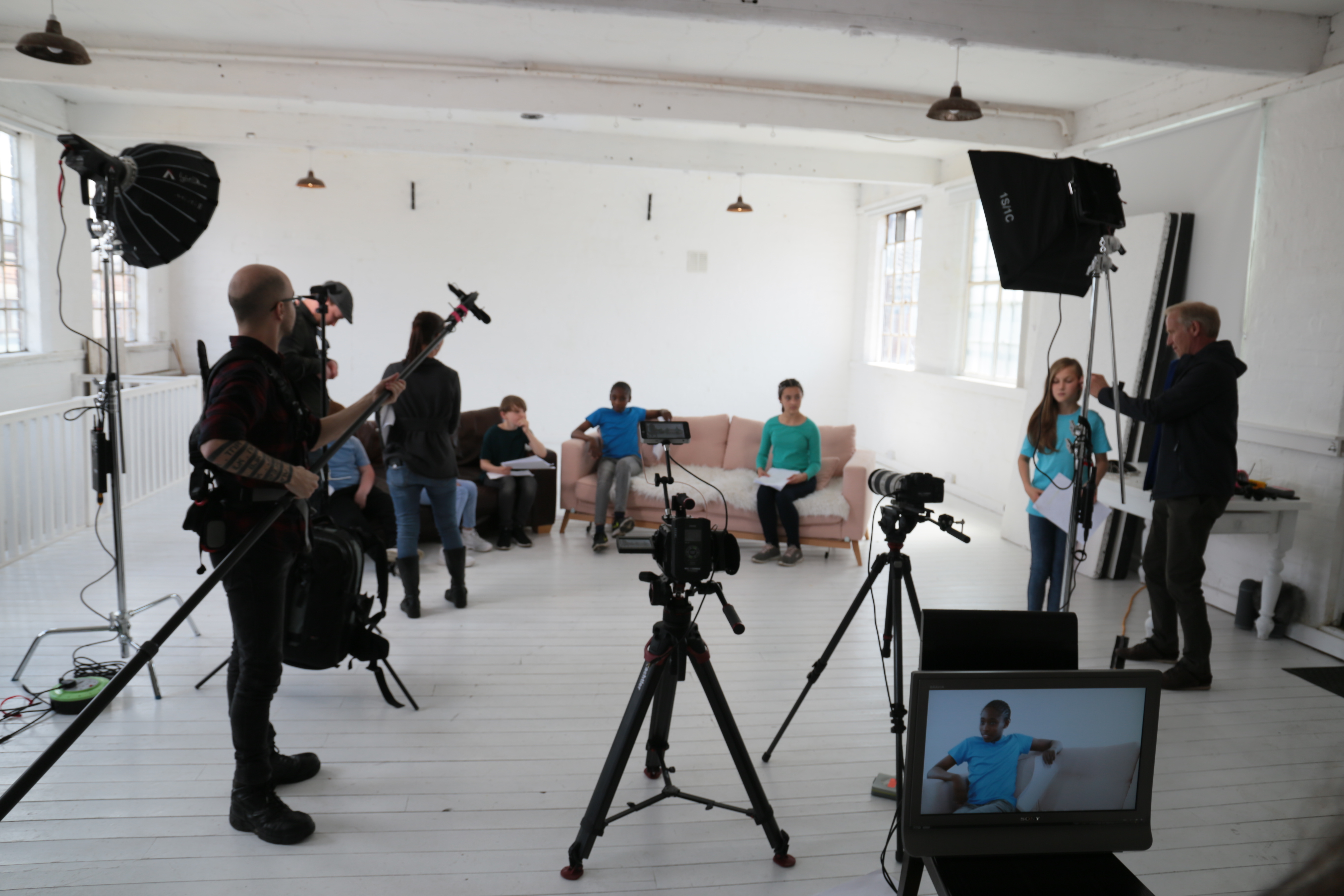Video production team setting up lights and cameras in studio.