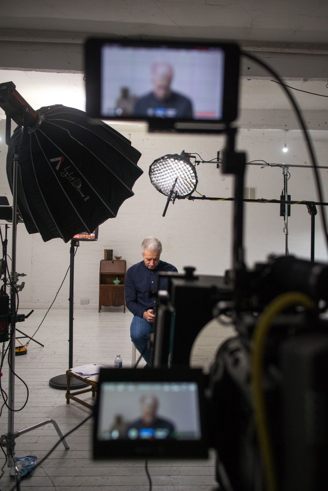 Video production setup with a man seated for an on-camera shoot.