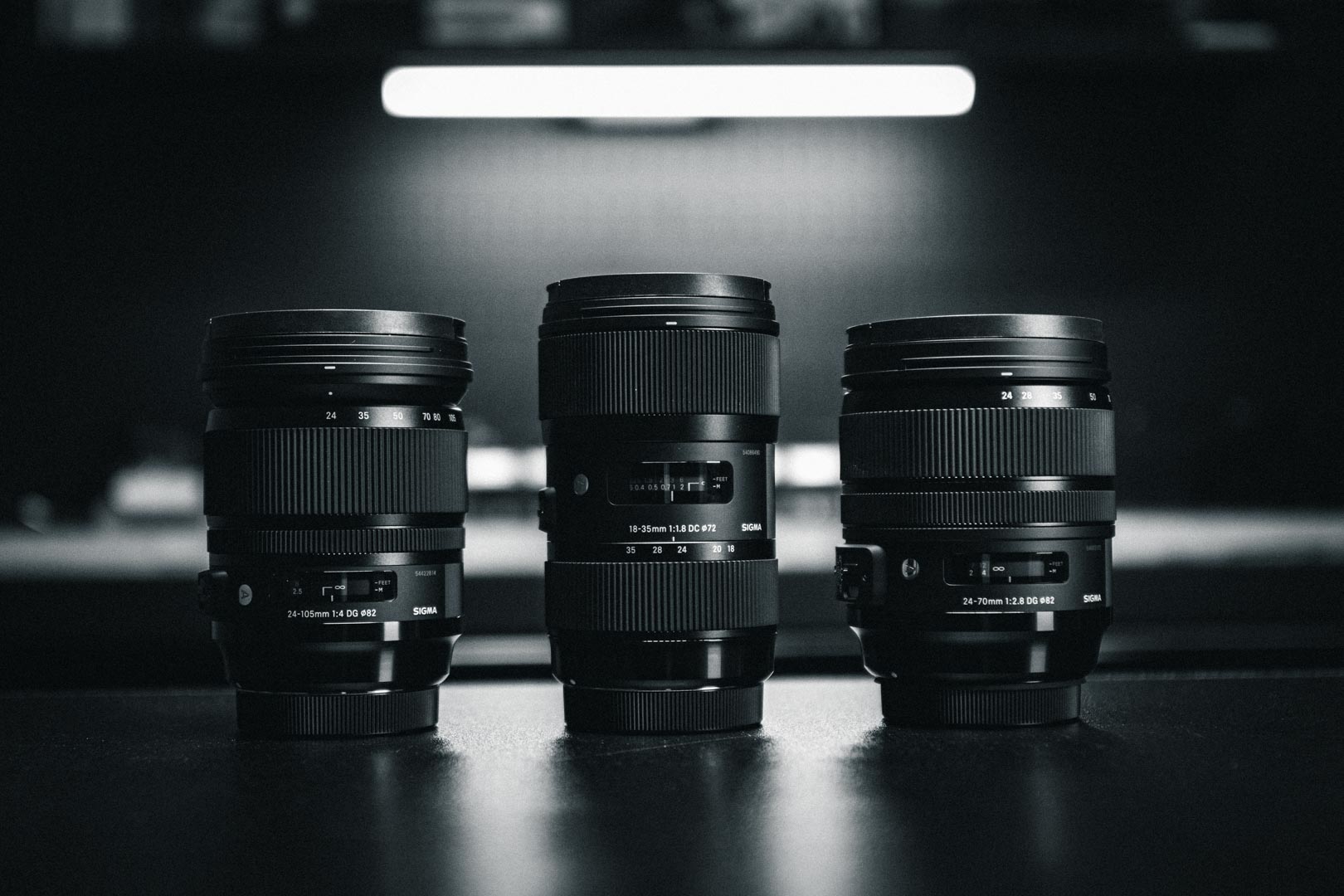 Three professional camera lenses lined up on a dark surface for video production.