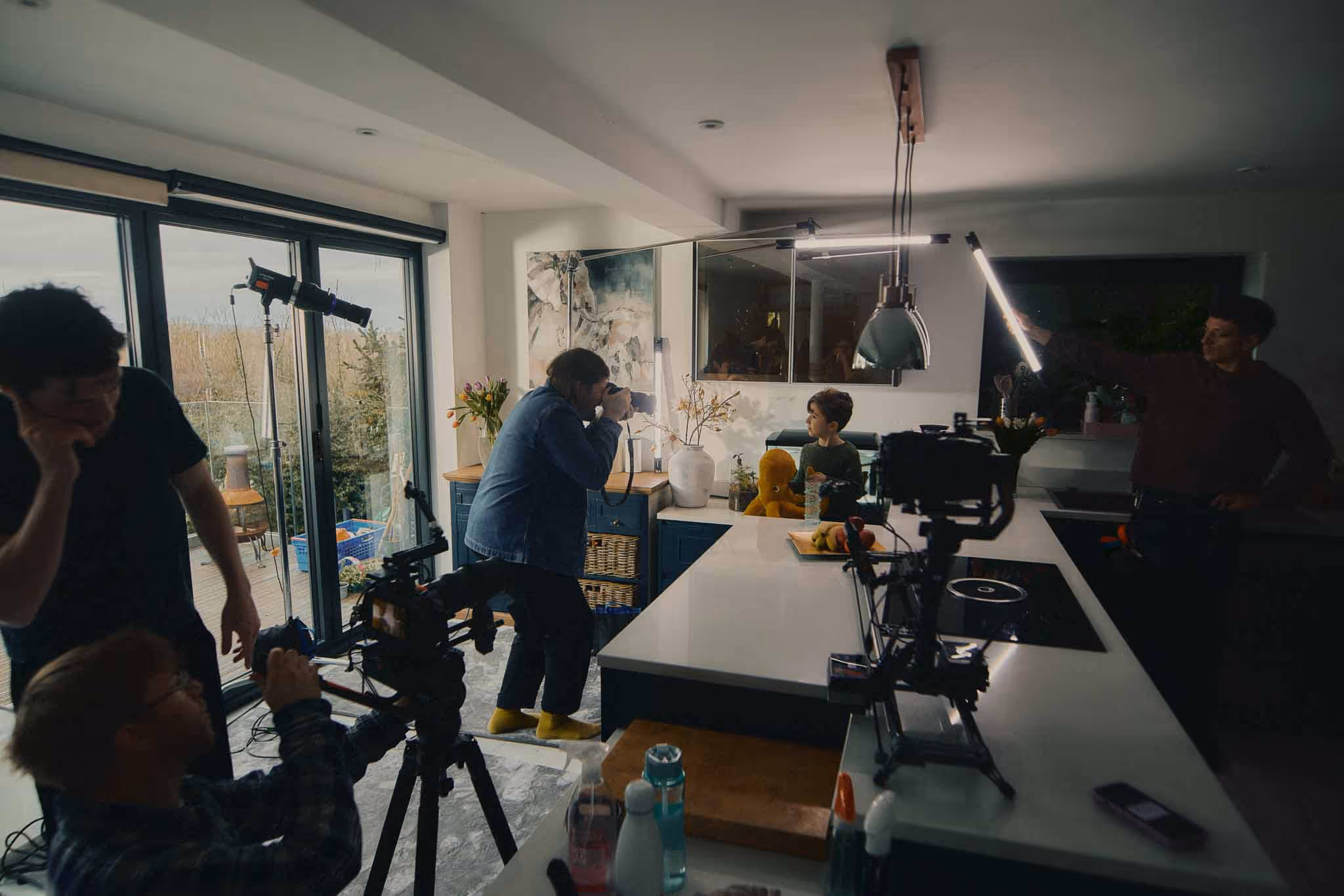 Film crew shooting a brand film kitchen scene with cameras and lighting equipment