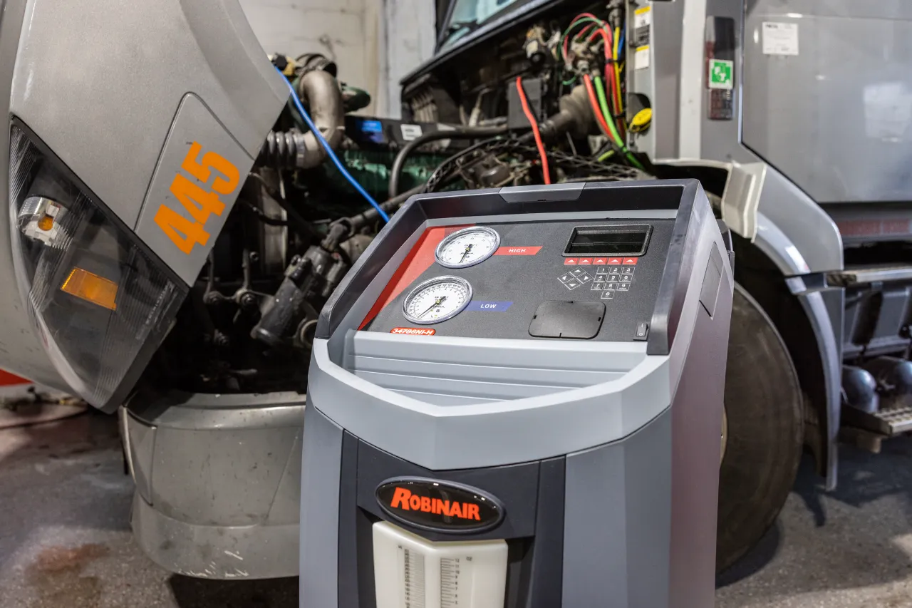 Robinair machine connected to a semi-truck during HVAC repairs, with hood raised and lines attached to the system.