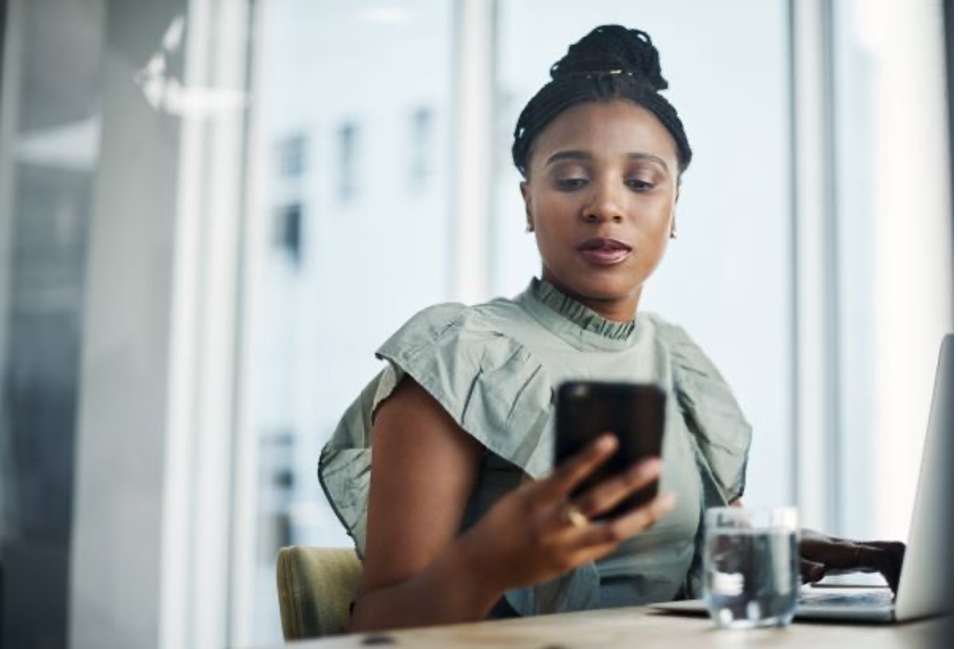 woman checks her cell phone at her desk