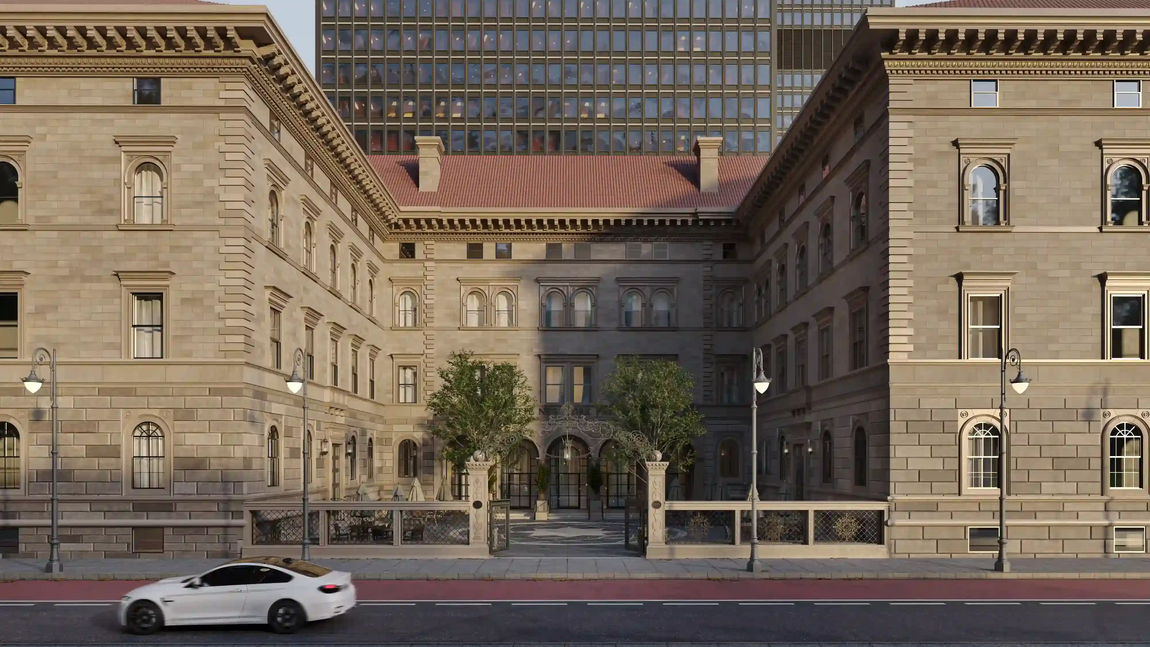 Historic stone building with arched windows and a gated courtyard featuring trees and outdoor seating.