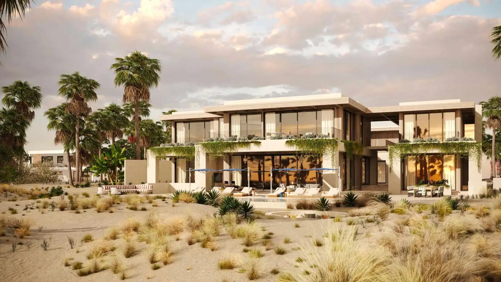 Modern two-story house with large glass windows, greenery, palm trees, and outdoor seating in a sandy landscape.