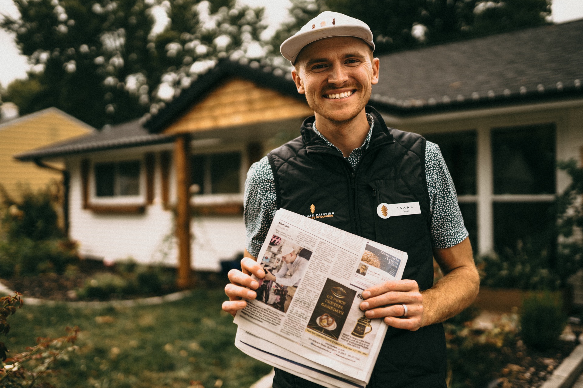 Isaac Mumma, owner of White Oak Painting, holding a newspaper outside a home.