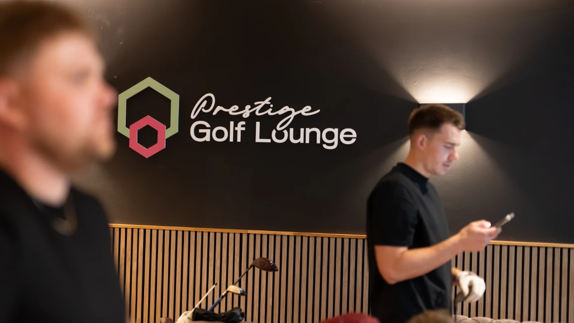 Prestige Golf Lounge logo on feature wall with players in foreground