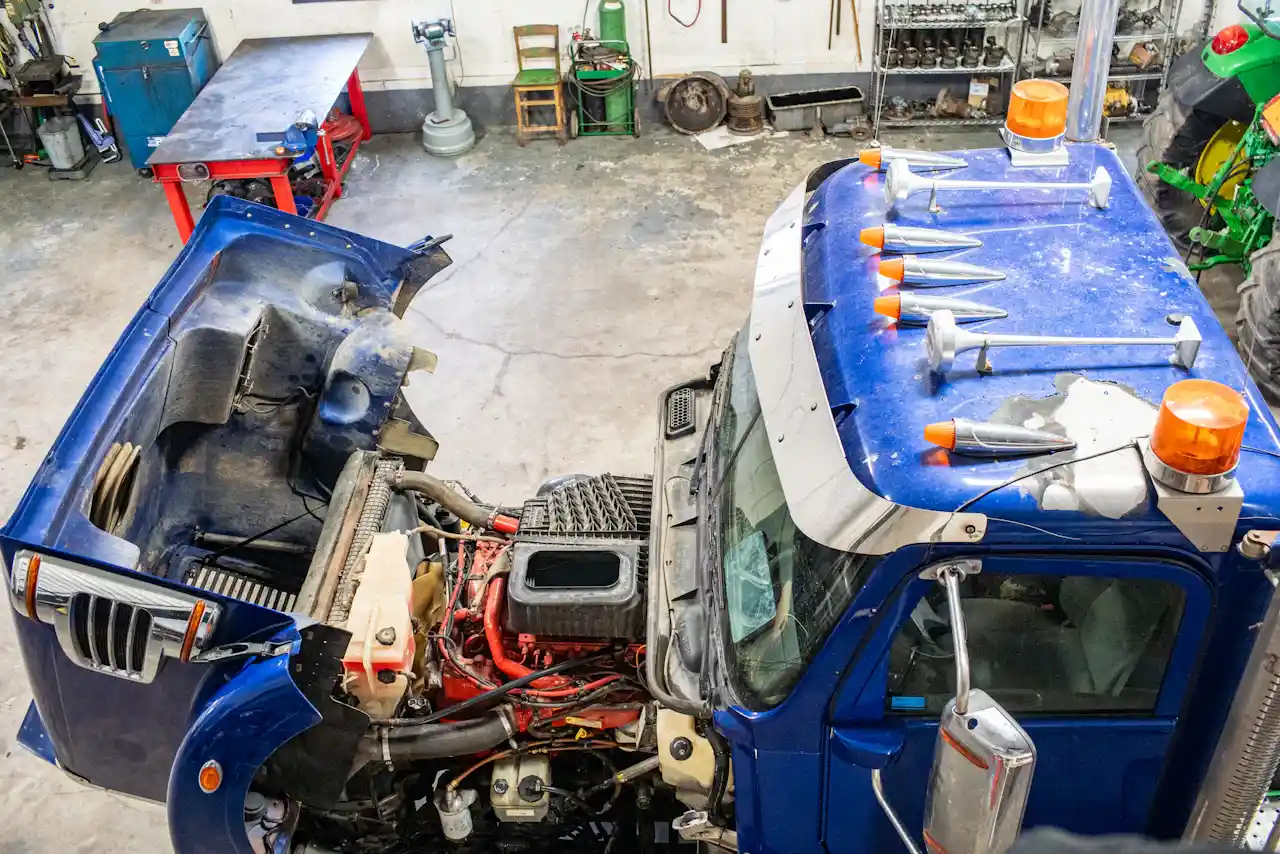 Fleet repair service for a heavy-duty truck, showing the hood open and engine exposed inside a commercial repair shop.