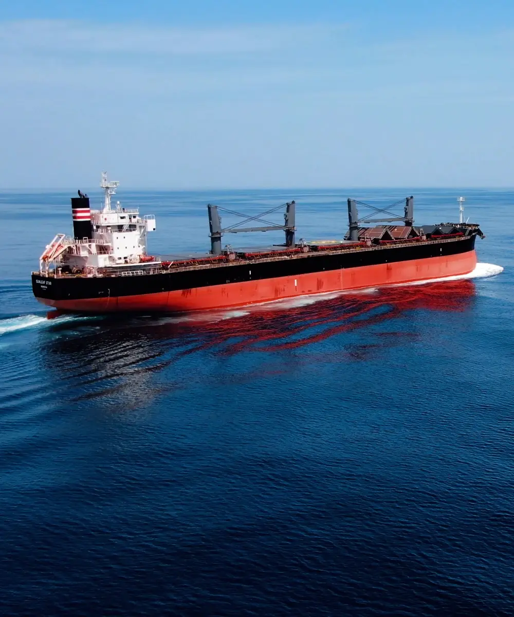An orange vessel full of cargo traveling by sea.