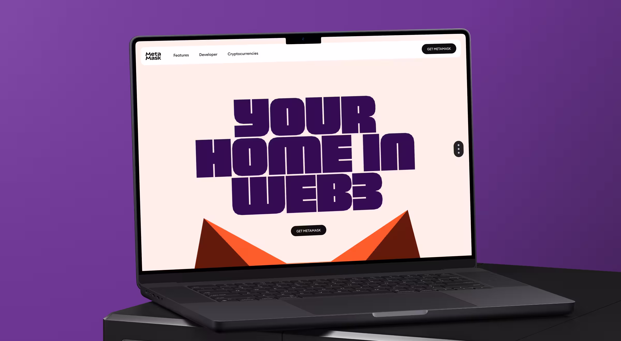 A laptop screen displays the MetaMask homepage with the bold tagline “Your Home in Web3” in large purple typography. The background is light pink, and MetaMask’s fox logo is partially visible at the bottom.