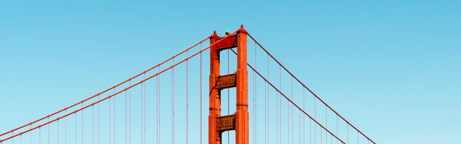 Close-up view of the top of the Golden Gate Bridge against a clear blue sky.