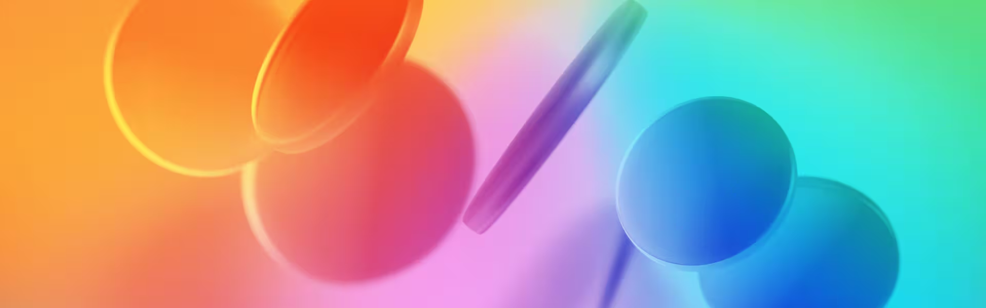 Abstract digital artwork featuring overlapping translucent circular and oval shapes in a vibrant gradient of warm oranges, reds, and pinks on the left, blending into cool blues, greens, and purples on the right.
