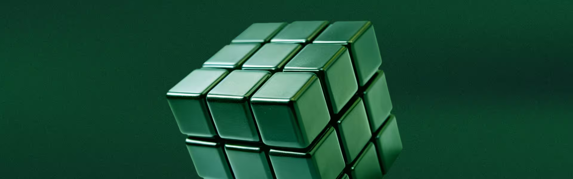 Close-up of a green metallic Rubik’s cube against a dark green background, symbolizing problem-solving, complexity, and structured design thinking