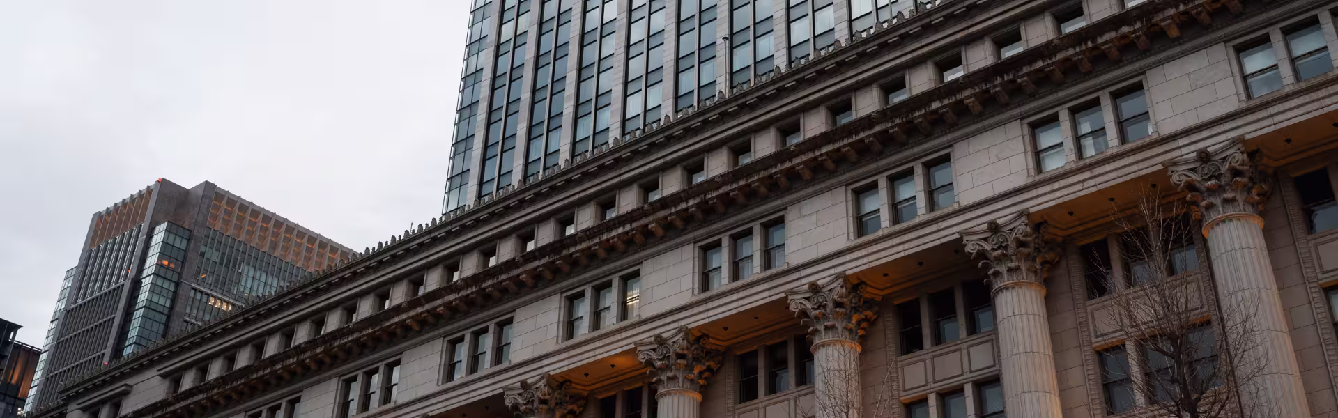 Historic architecture with classical columns alongside modern skyscraper in downtown cityscape, blending traditional and contemporary design