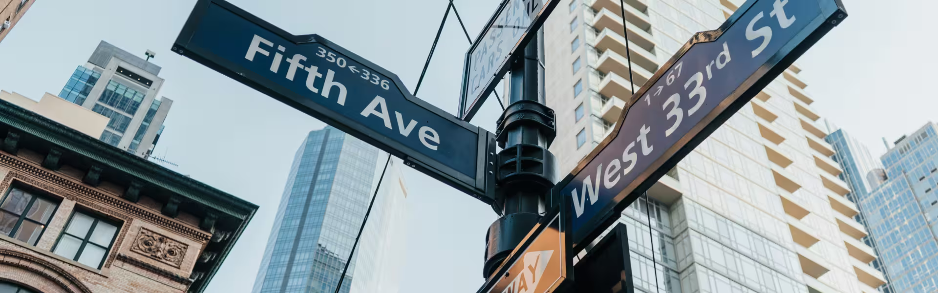 Street signs at Fifth Avenue and West 33rd Street in Manhattan, New York City with modern skyscrapers in the background