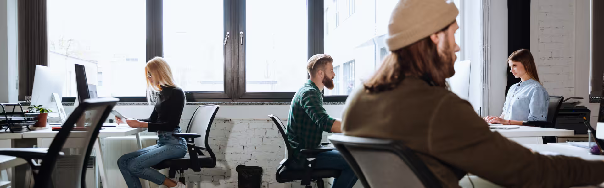 Modern open office space with young professionals working at desks on computers in a collaborative environment