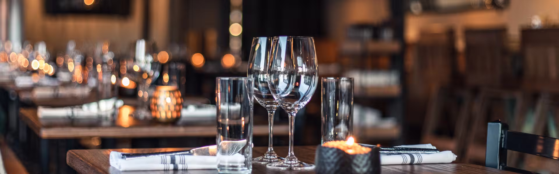 Elegant restaurant table setting with wine glasses, candles, and folded napkins — header image for Lazarev.agency’s hospitality and restaurant web design