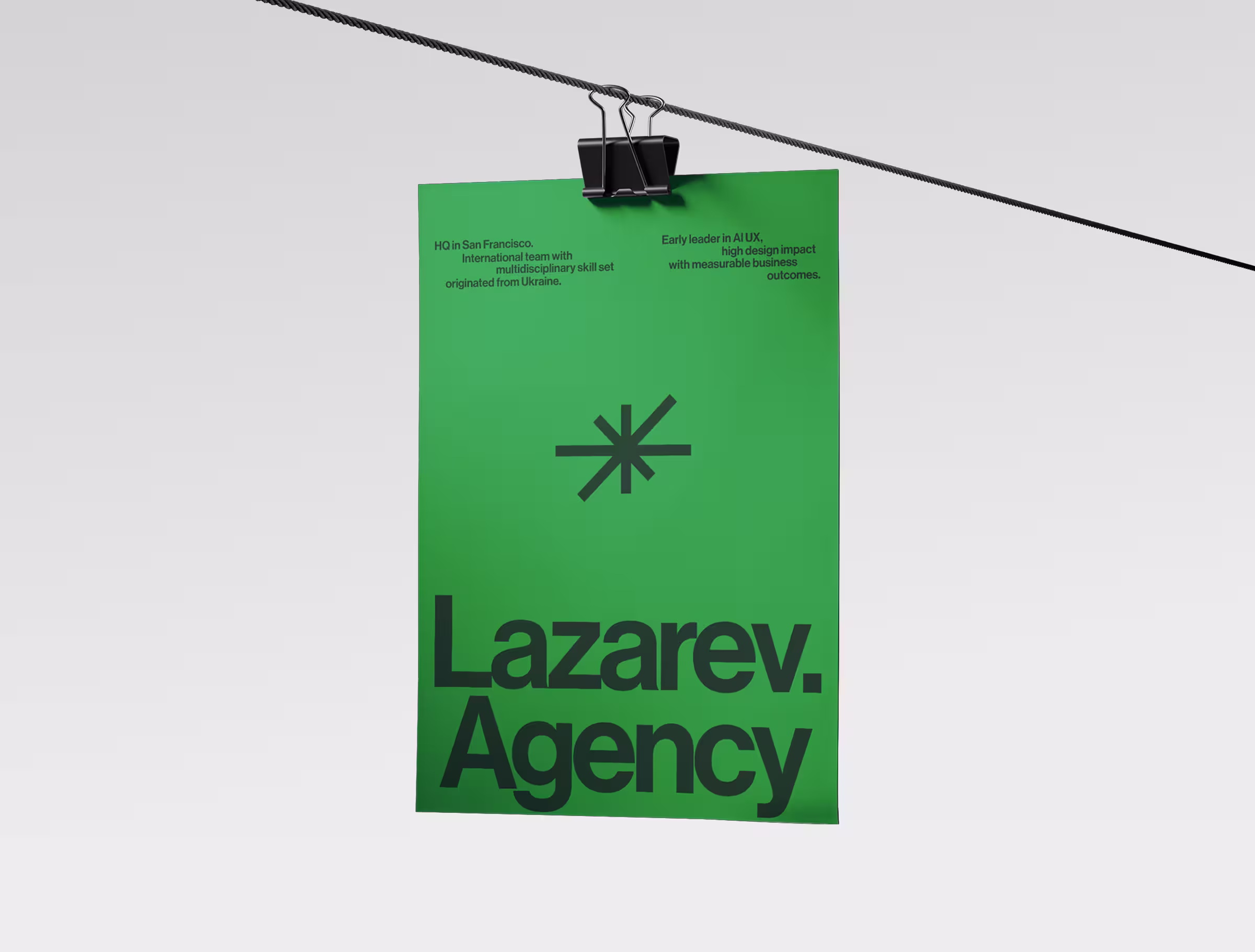 Green poster with the Lazarev.agency logo and messaging, hanging from a clipped wire against a minimal light background