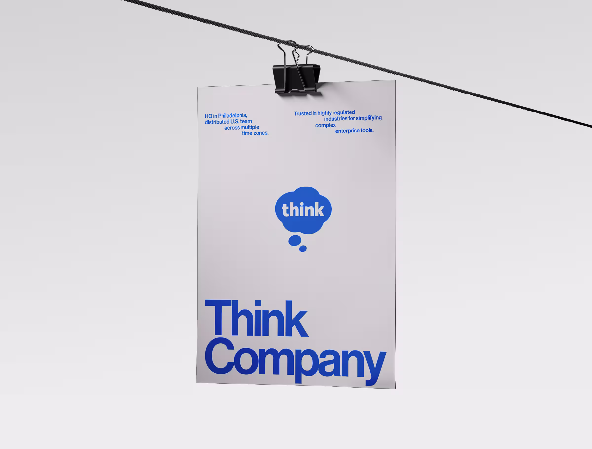 White poster with blue ‘Think Company’ branding and a speech-bubble logo, hanging from a clipped wire against a minimal light background