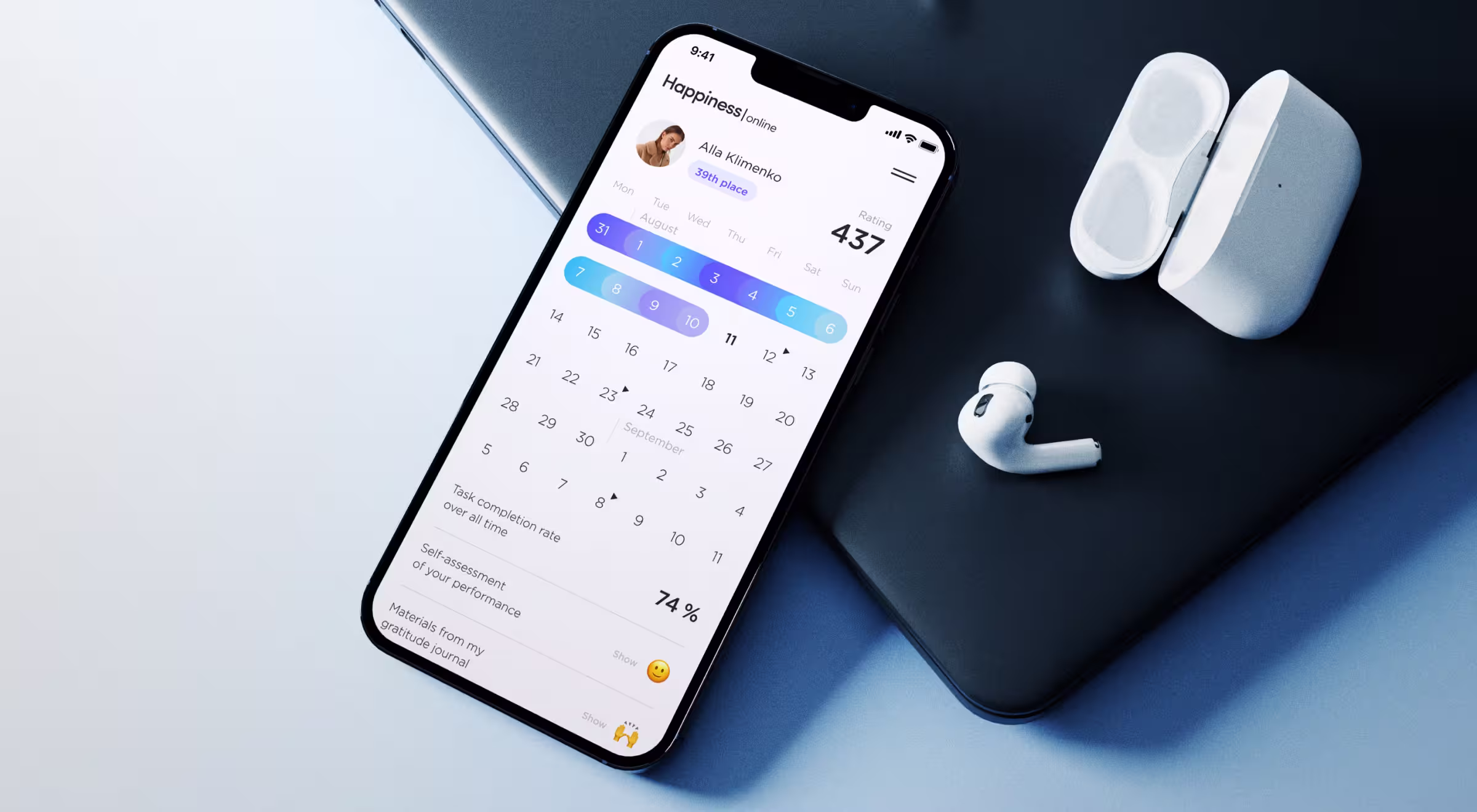 Smartphone displaying a wellness app calendar and productivity stats, placed on a laptop next to wireless earbuds in a charging case