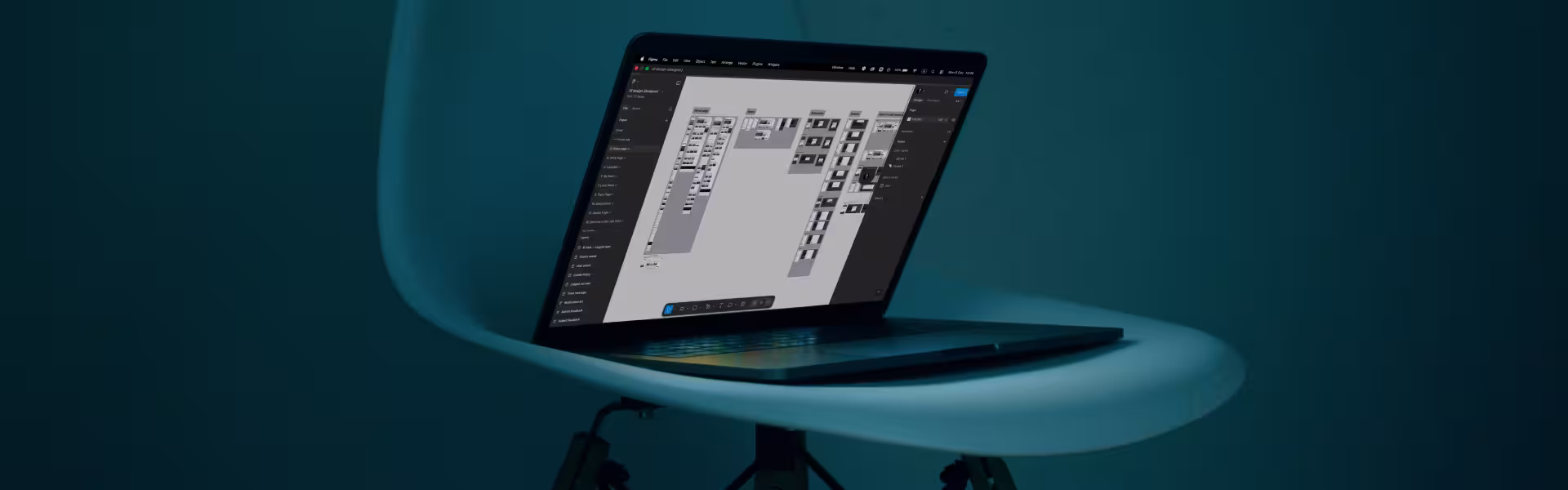 Laptop placed on a sculptural stand, displaying a complex design workspace with multiple UI screens and components arranged on a large canvas in a professional design tool interface