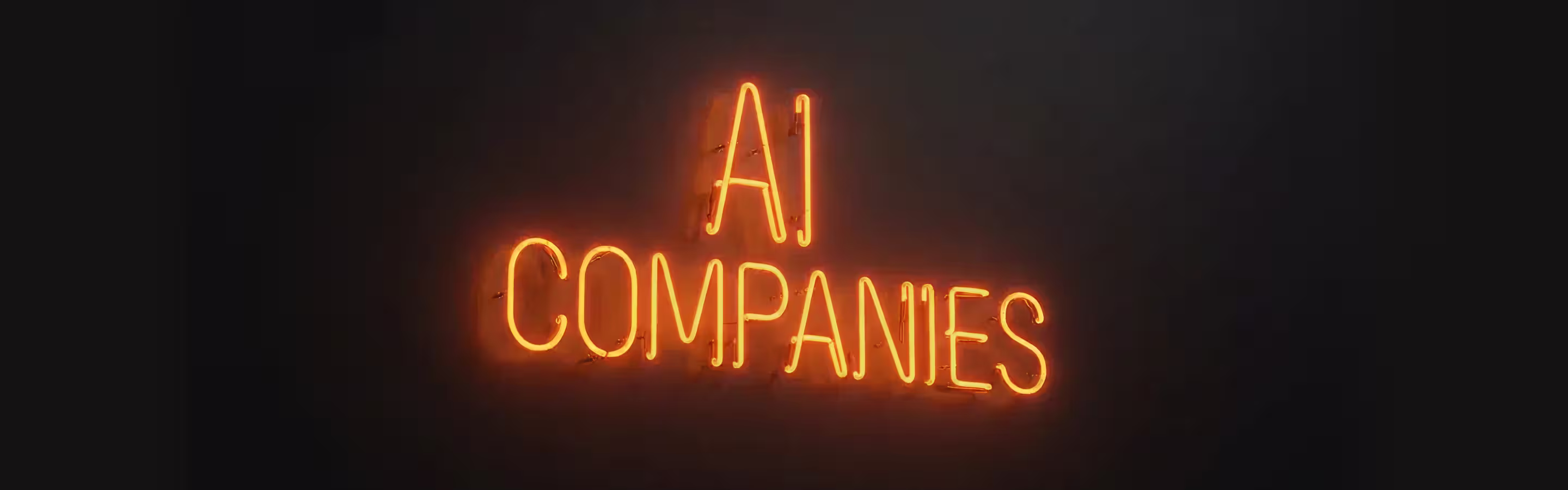 Neon sign displaying the text "AI COMPANIES" in bright orange against a dark background, emphasizing innovation in artificial intelligence.