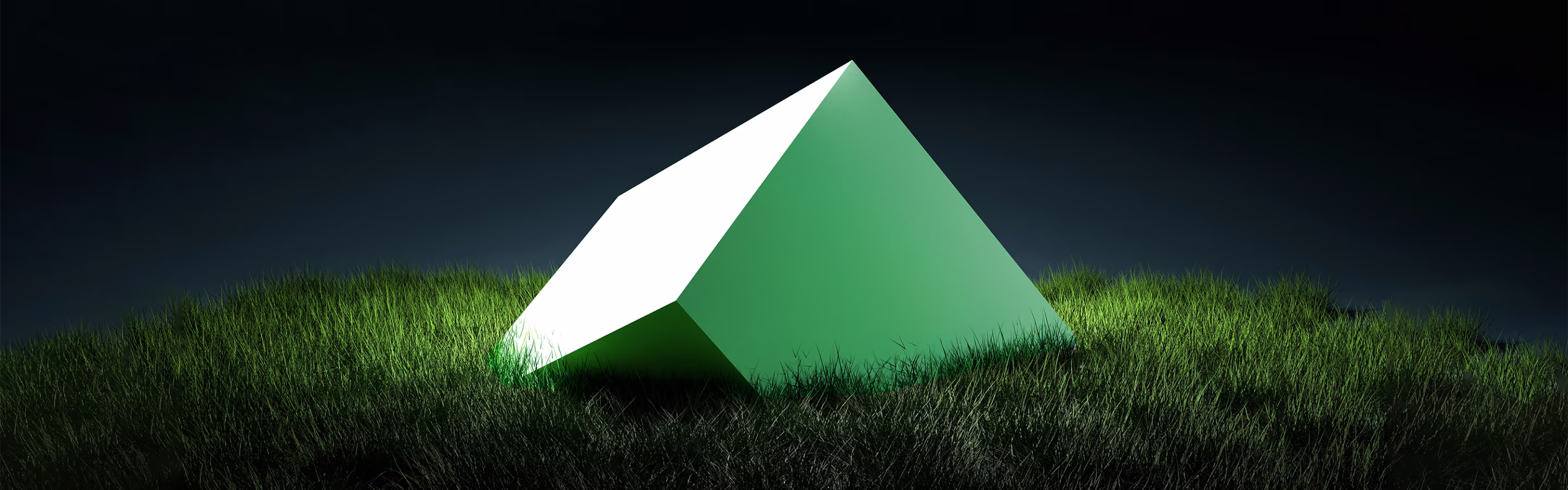 A large, green, illuminated pyramid sits on vibrant grass against a dark background, creating a striking contrast.