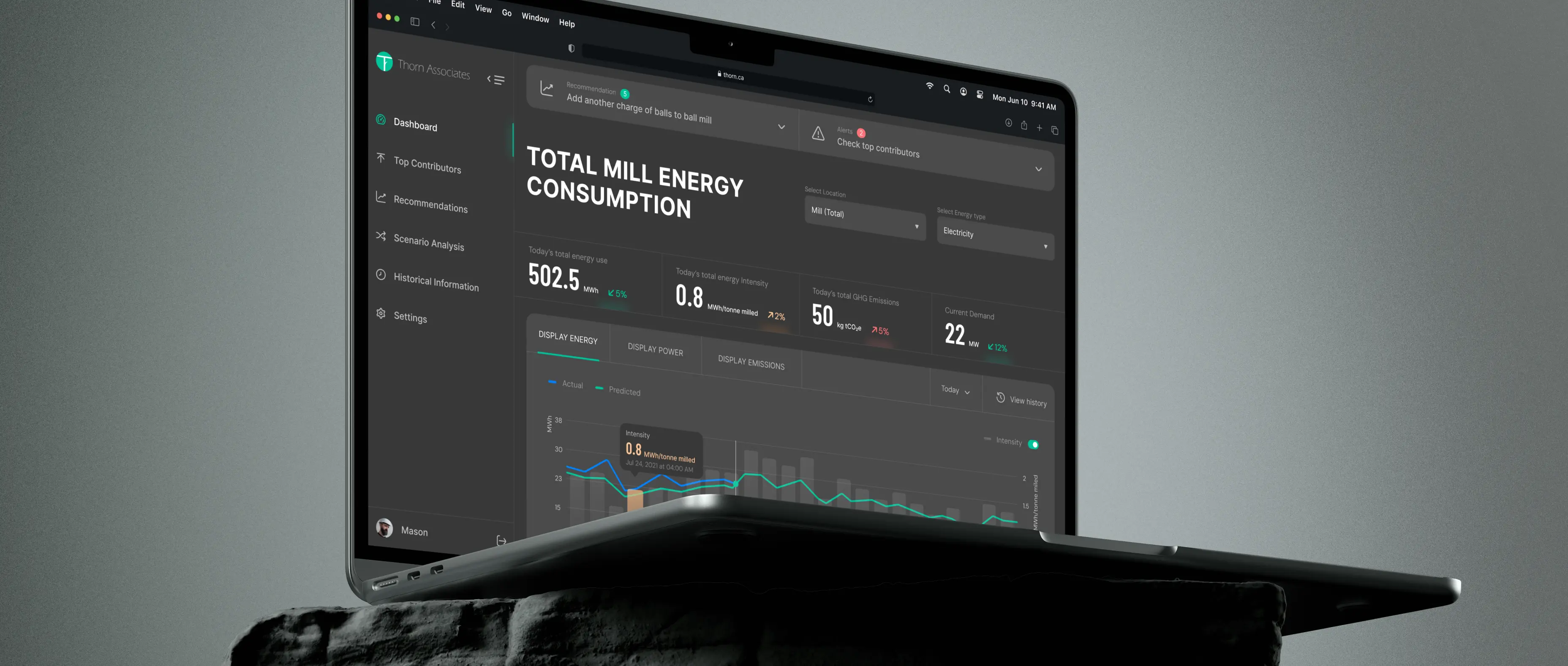 A laptop displays a dark-themed dashboard showing total mill energy consumption metrics and graphs.