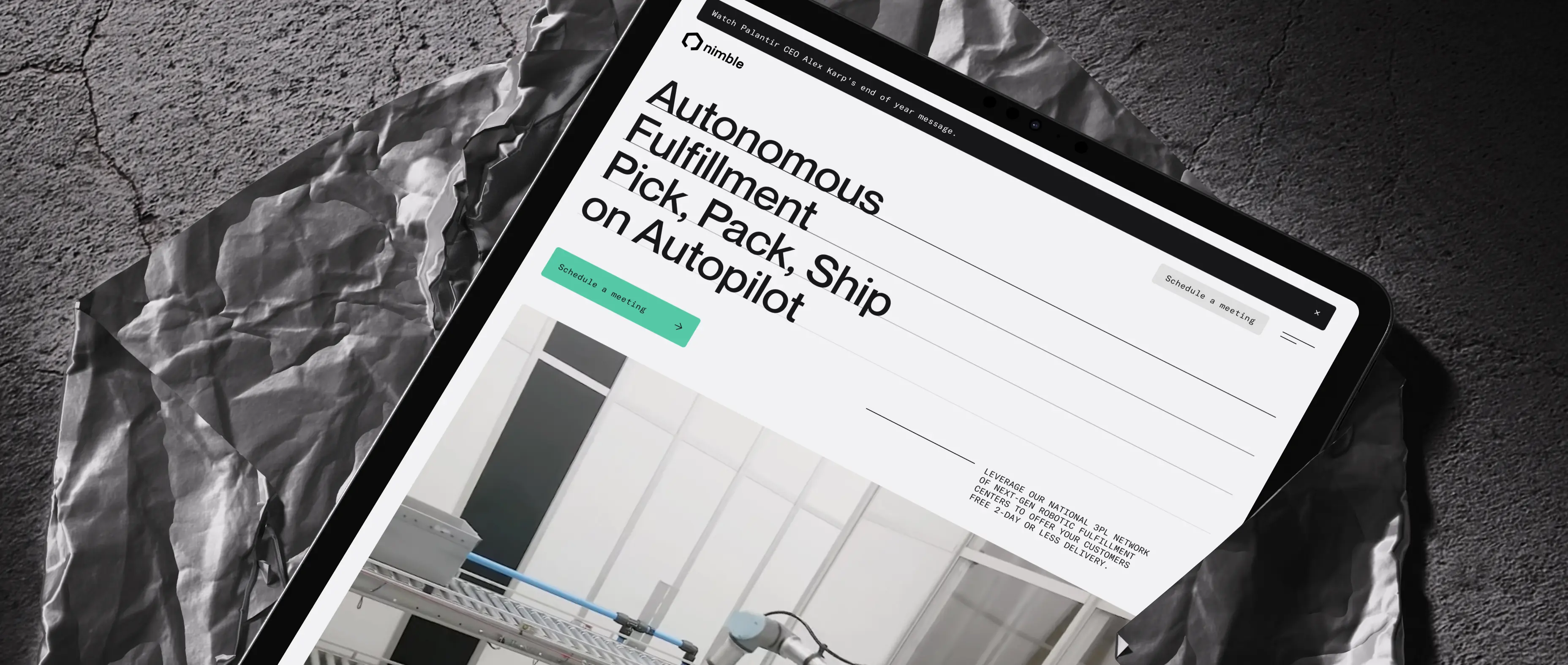 Angled tablet mockup on a textured industrial surface shows the Nimble website hero section with the headline “Autonomous Fulfillment Pick, Pack, Ship on Autopilot” and a warehouse robotics preview.
