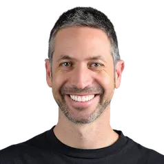 Smiling man with short dark hair and beard wearing a black shirt against white background.
