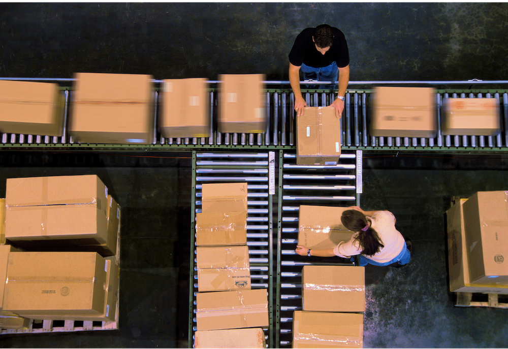 A female Veho driver picking a package from car's boot to deliver.