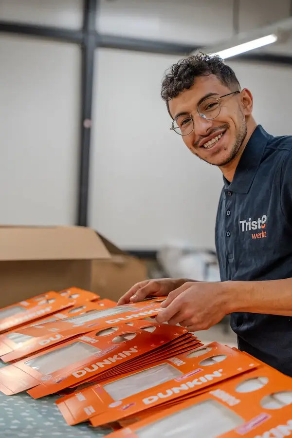 Medewerker van Tristo bezig met inpakwerk en assemblage van verpakkingen in een logistieke werkomgeving.