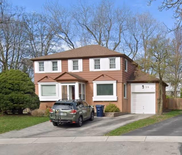 Two-story suburban house with brown siding and brick exterior, a driveway with an SUV parked, and a garage with the number 356.