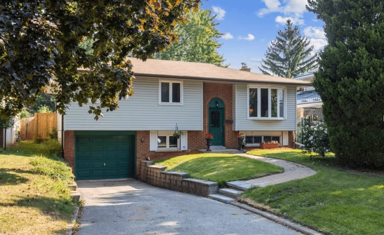 Single-story suburban house with green front door and garage, surrounded by green lawn and trees.
