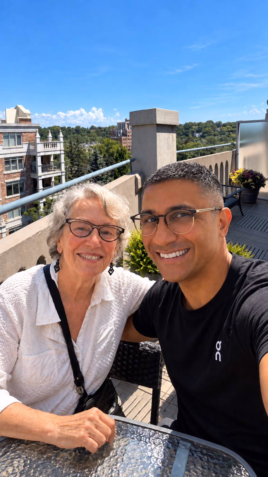 Shen Walji smiling with an older woman on a rooftop terrace.