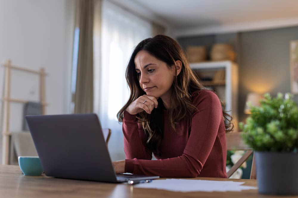 Woman concentrating while reviewing information on her laptop, symbolizing research and understanding of ADHD DSM-5 criteria.
