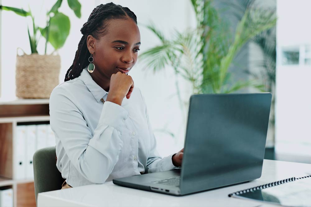 Woman working on a laptop in a bright office, symbolizing the growing understanding and research developments in ADHD science.