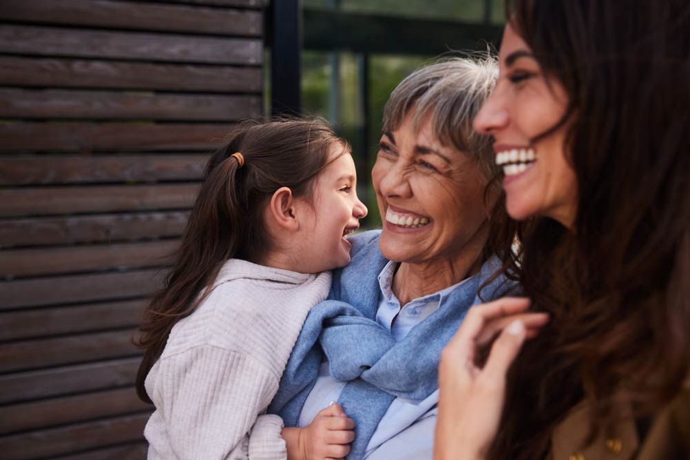 Three generations of women smiling together outdoors, symbolizing how ADHD symptoms evolve across childhood, adulthood, and later life.