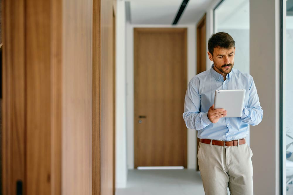 Man holding a tablet while walking in a hallway, symbolizing focus and restlessness in hyperactive-impulsive ADHD.
