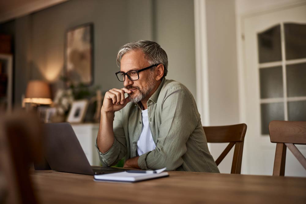 A middle-aged man focuses on his laptop during an online ADHD assessment at home, representing adult ADHD evaluation and self-reflection.