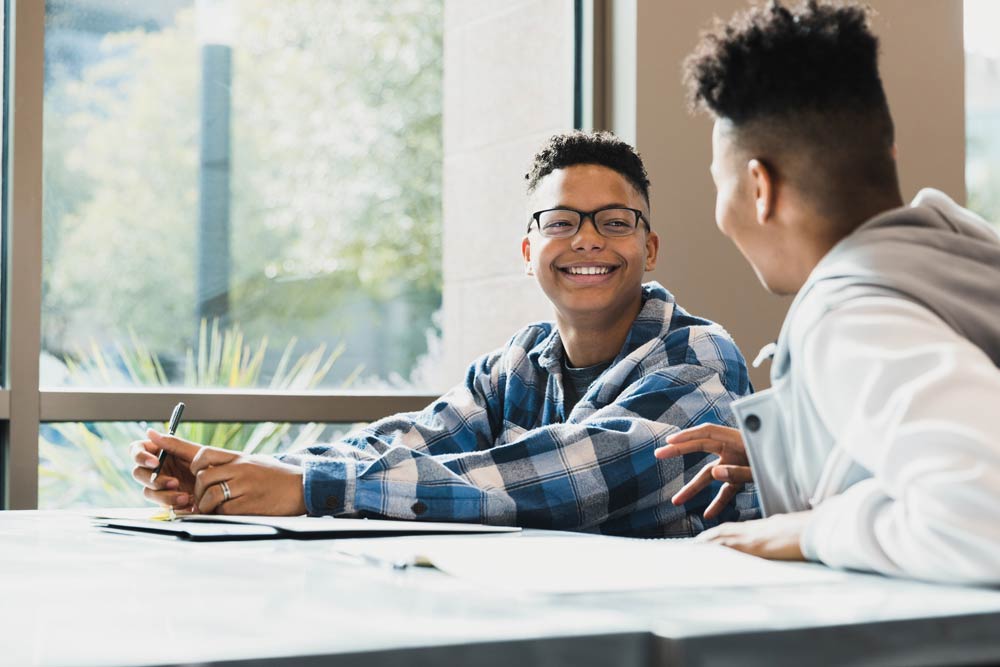 Smiling teenage student talking with a friend in class, representing strengths-based self-identity for teens with ADHD.