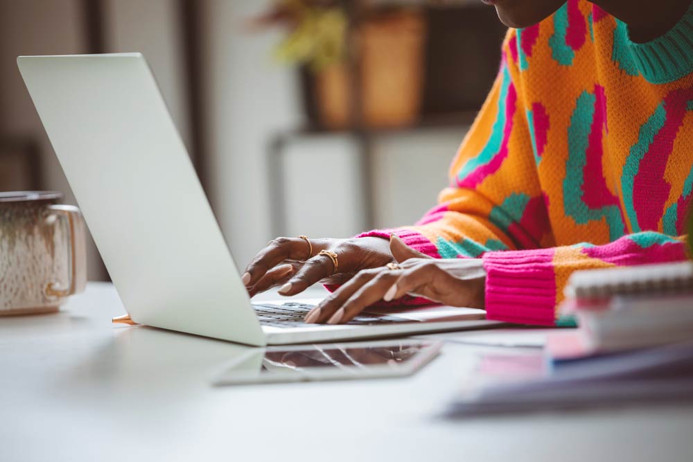 A person wearing a colourful sweater typing on a laptop, symbolizing creativity, focus, and the connection between ADHD and innovative thinking at work.