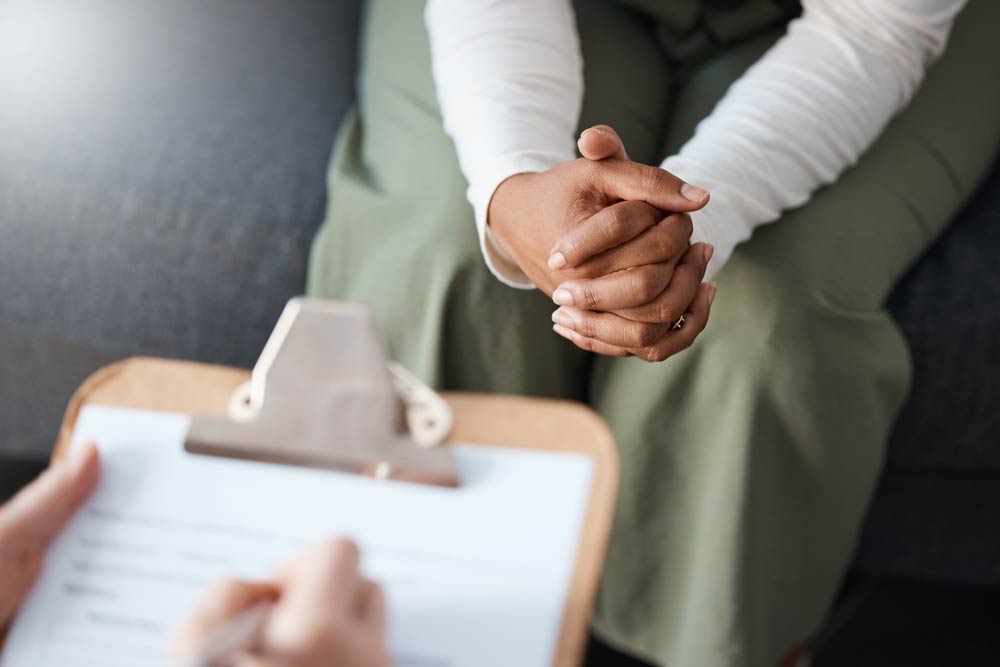 A person sitting with hands clasped during a clinical consultation, symbolizing the importance of professional ADHD assessment compared to self-screening tools.