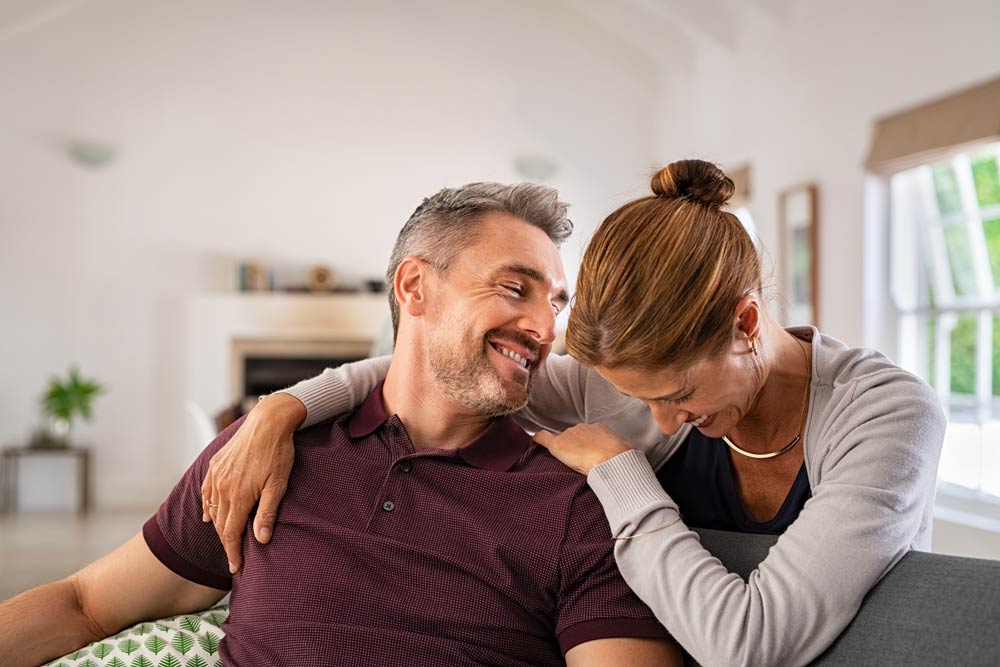 Smiling couple sitting close together on a couch, symbolizing patience and empathy in ADHD relationships.
