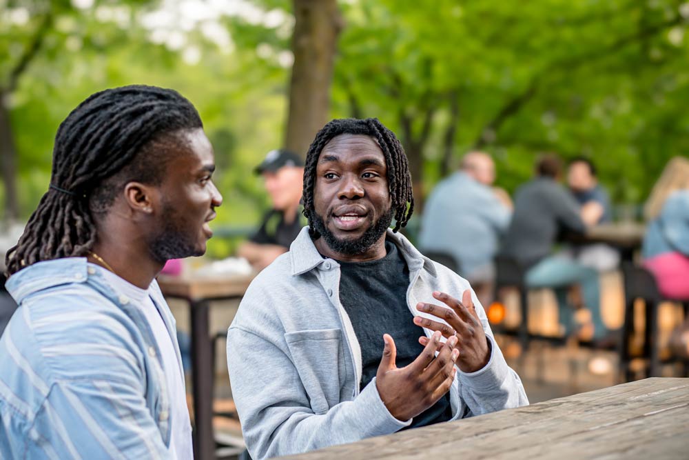 Two men having a thoughtful conversation outdoors, symbolizing explaining ADHD behaviours to those who don’t understand.