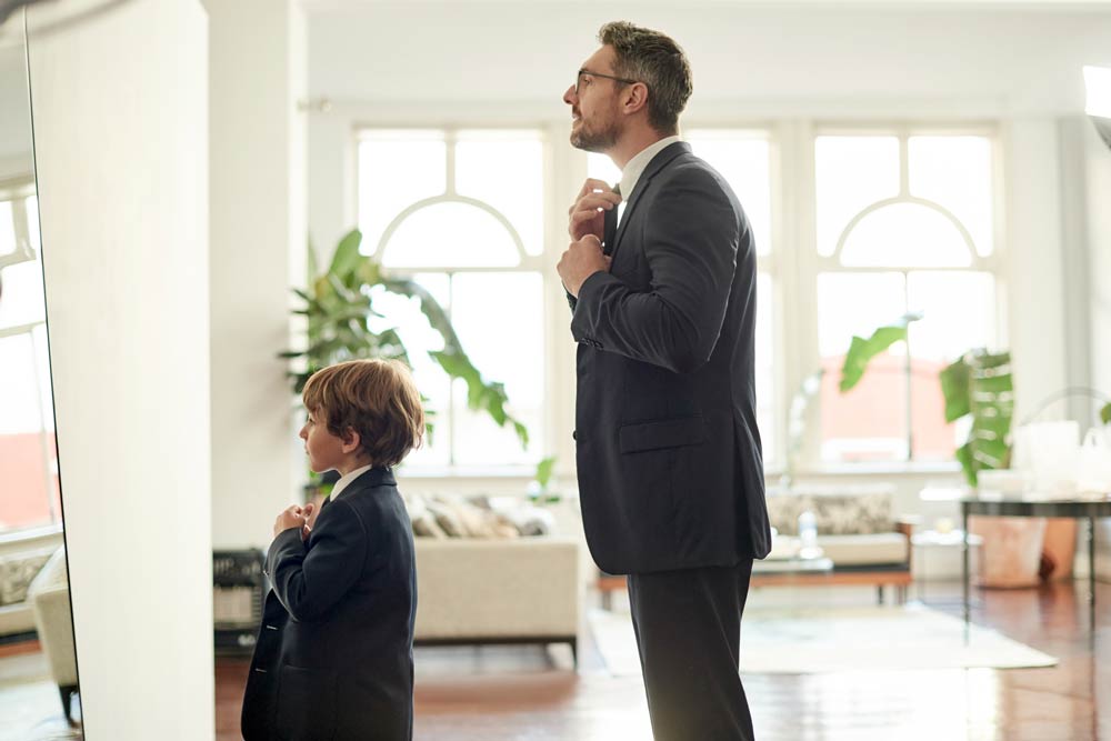 Father and son adjusting their ties in the mirror, symbolizing how ADHD often persists from childhood into adulthood.