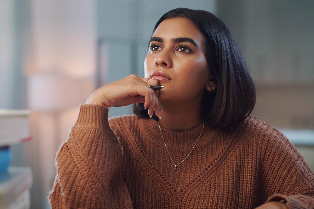 Thoughtful woman holding a pen, reflecting on memory and focus, representing the difference between normal forgetfulness and ADHD-related cognitive challenges.