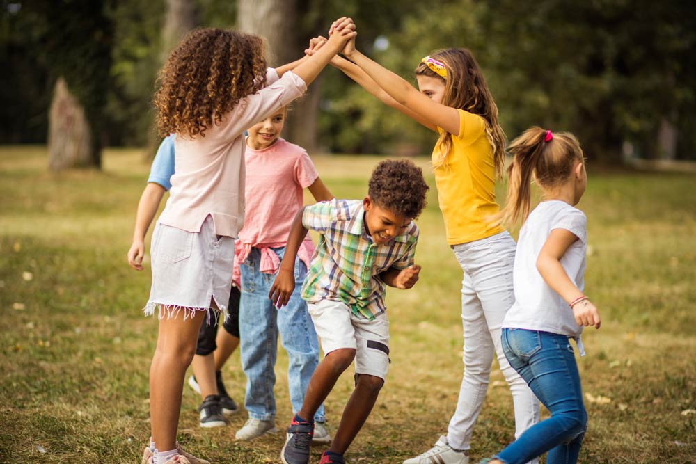 A group of children play together outdoors, illustrating how structured activities and social skills development help kids with ADHD build friendships.