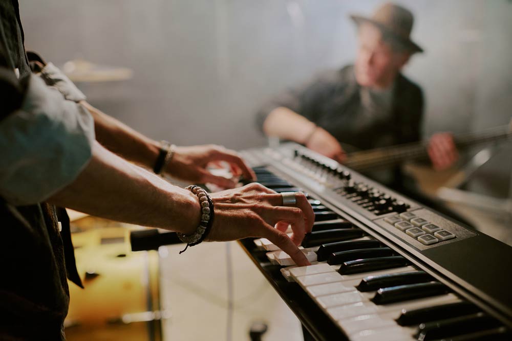 A musician playing a keyboard during band practice, representing how creative outlets like music and art can support focus, emotional regulation, and well-being in people with ADHD.