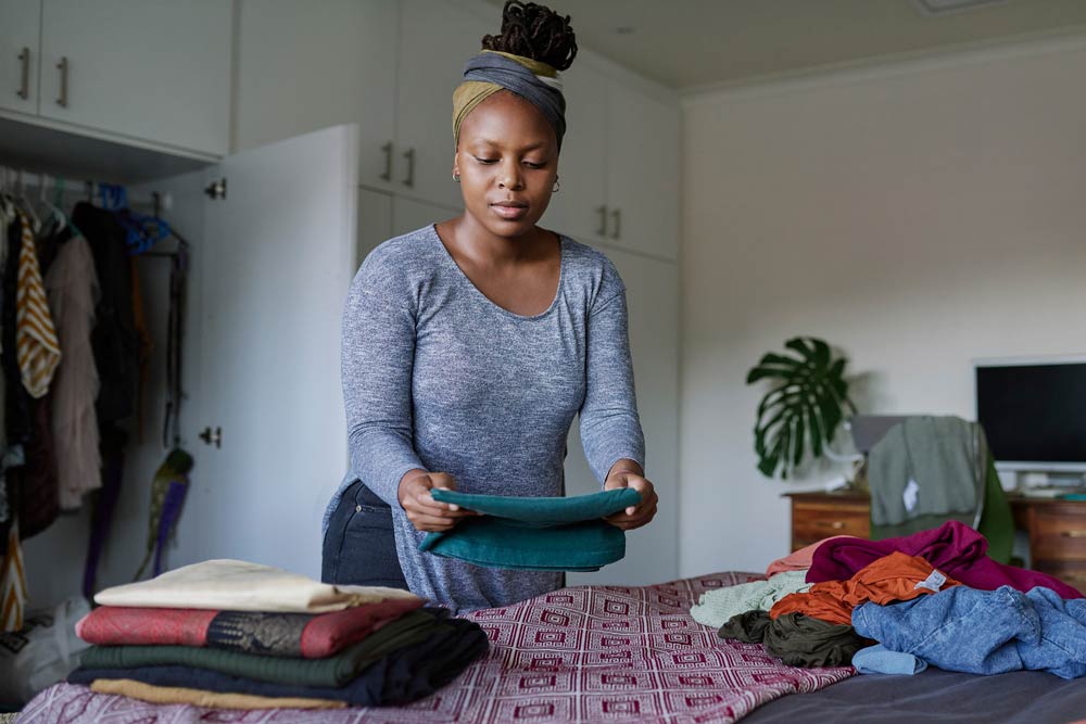 A woman folding laundry on her bed, symbolizing how completing small tasks right away using the 2-Minute Rule can help individuals with ADHD stay organized and productive.